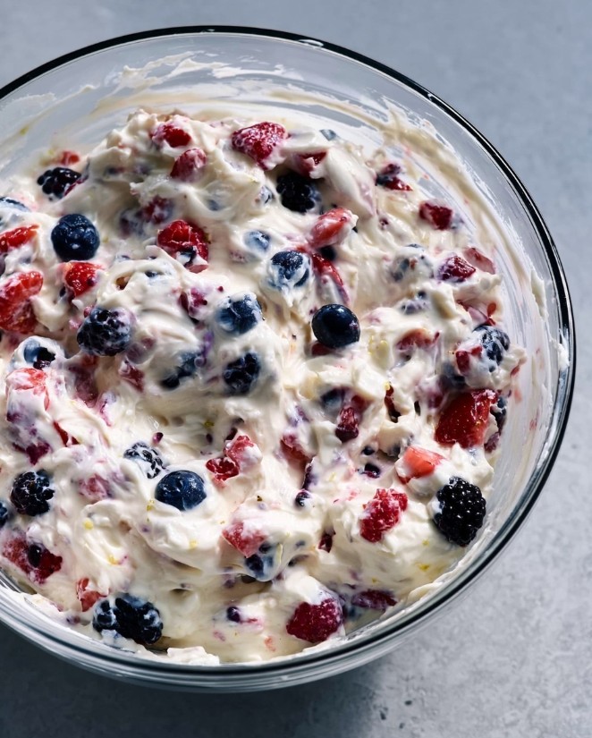 Folding the Salad - Low carb berry cheesecake salad in a glass bowl, berries mixed into thick white base