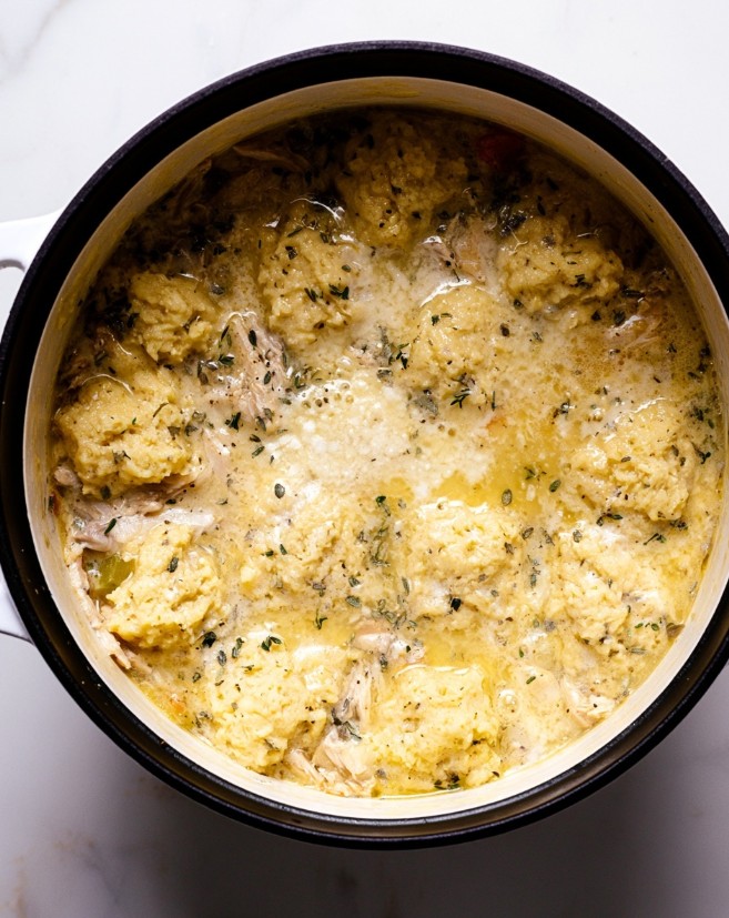 Simmering the Soup - Low-carb herbed chicken and dumplings cooking inside a pot, resting on a thick broth spotted with green herbs