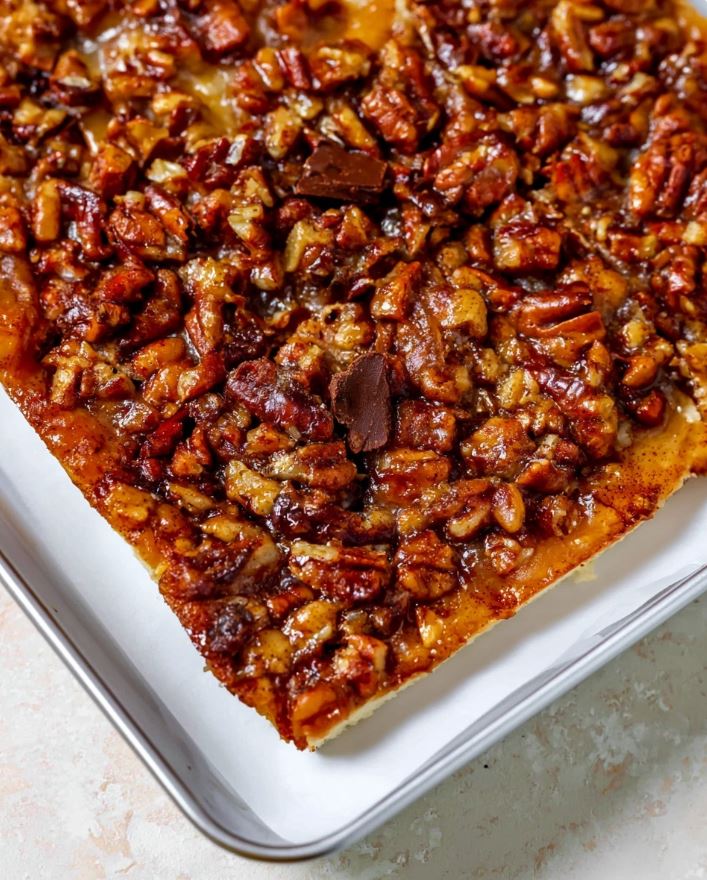 Keto Pecan Pie Bars - An uncut slab of the baked bars cooling on parchment paper, highlighting the shiny caramelized pecan topping