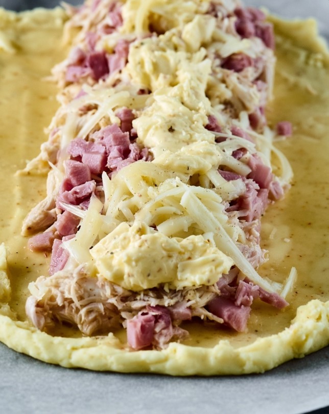 Golden Keto Chicken and Ham Stromboli — low carb chicken and ham stromboli dough stretched on baking paper and creamy filling in center