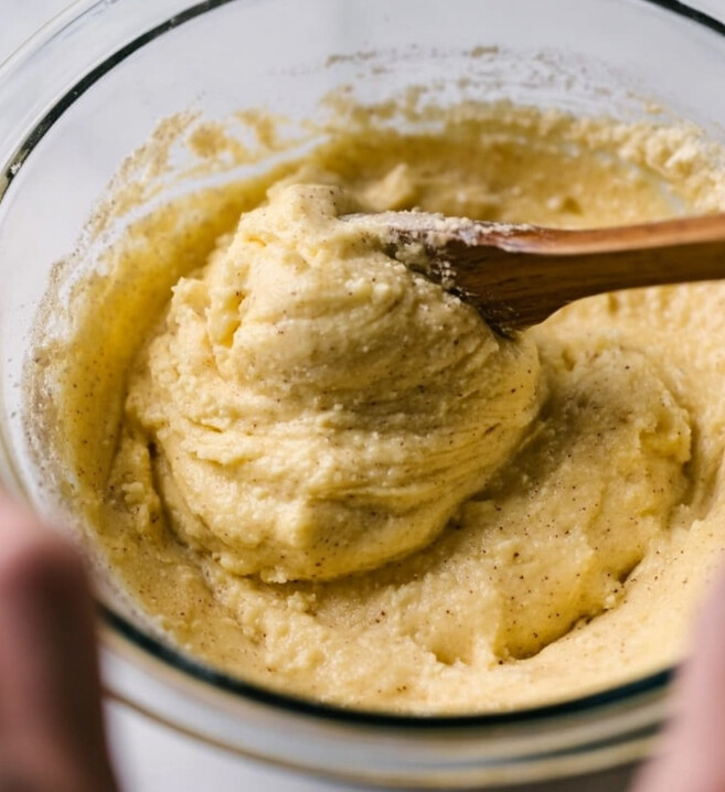 Crispy Keto Almond Flour Churros That Snap — thick keto almond flour churro dough being mixed in a glass bowl with a wooden spoon until elastic