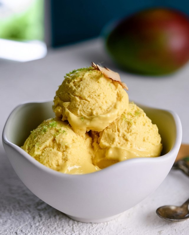 Creamy Tropical Mango Ice Cream - Bright yellow, velvety keto mango ice cream served in a light ceramic bowl.