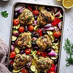 Mediterranean sheet pan chicken roasted with zucchini, blistered cherry tomatoes, and scattered feta cheese