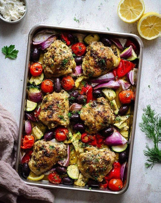 Mediterranean sheet pan chicken roasted with zucchini, blistered cherry tomatoes, and scattered feta cheese