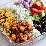 Sliced chipotle chicken, charred corn, black beans, and cilantro-lime rice arranged in a glass meal prep container
