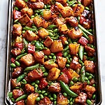 Roasted teriyaki chicken and vegetables on a sheet pan with dark caramelized pineapple edges