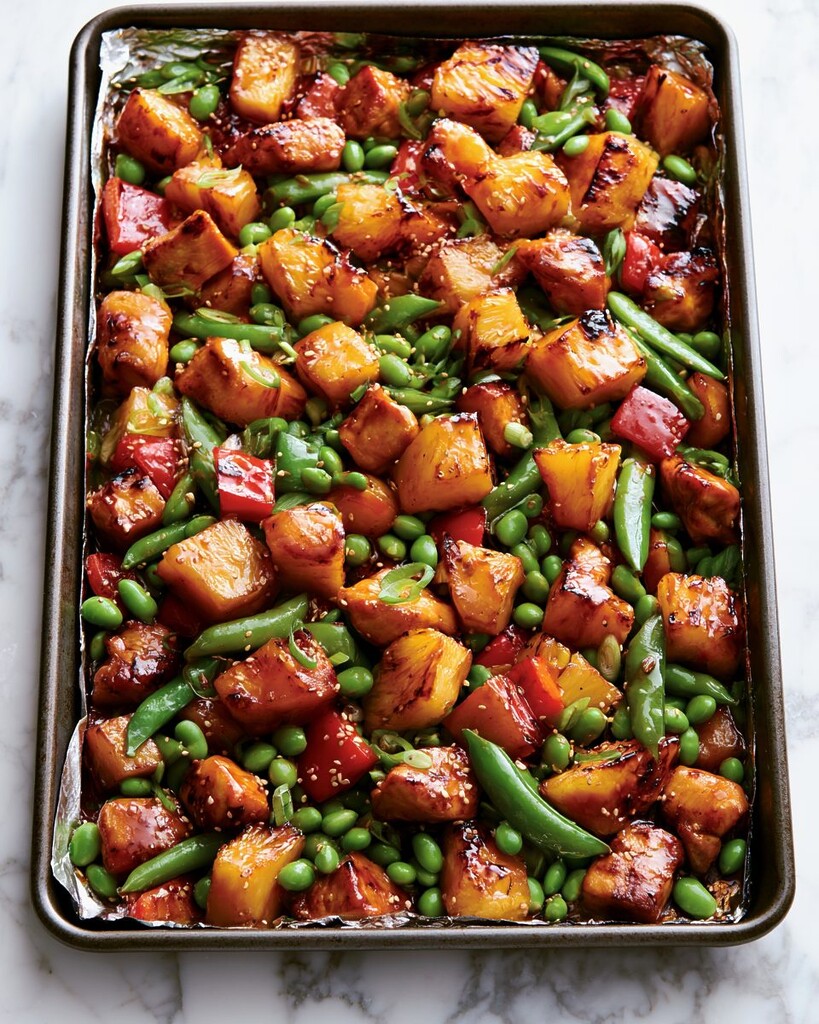 Roasted teriyaki chicken and vegetables on a sheet pan with dark caramelized pineapple edges