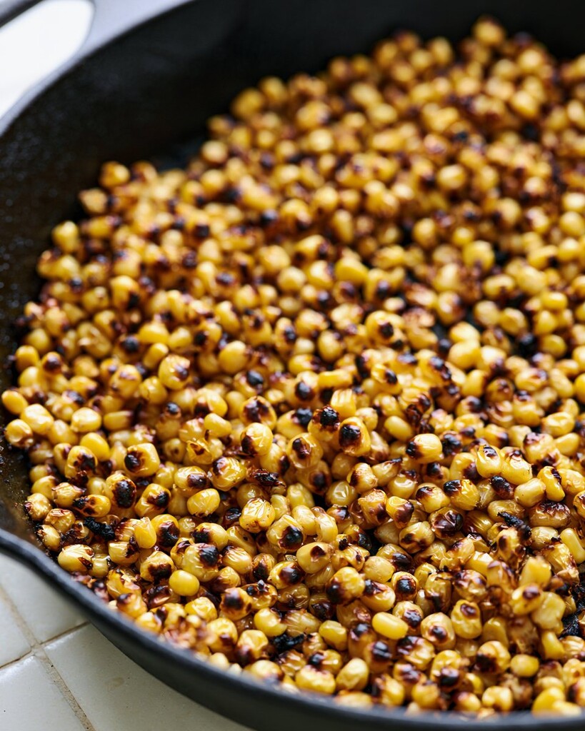 Corn kernels charring in a black cast-iron skillet