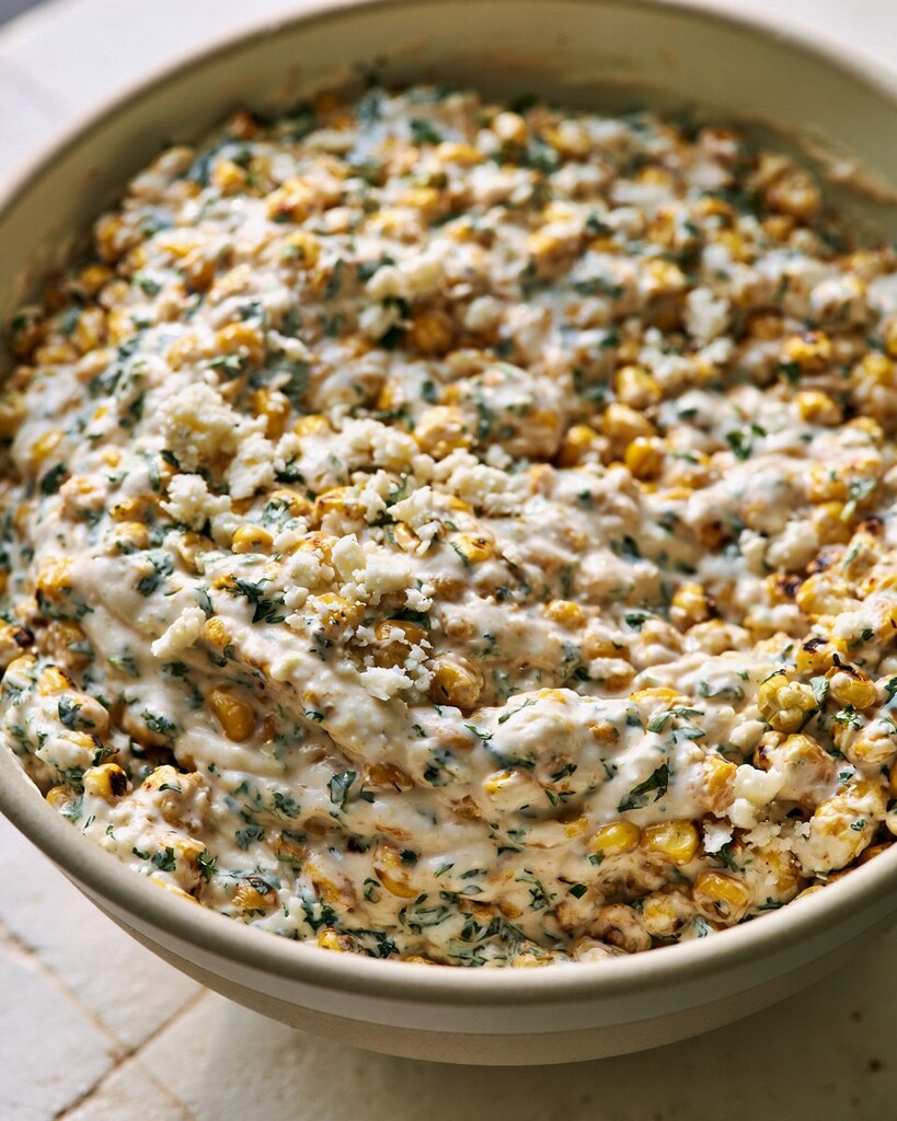 Charred corn salad mixed with creamy dressing and cilantro in a ceramic bowl