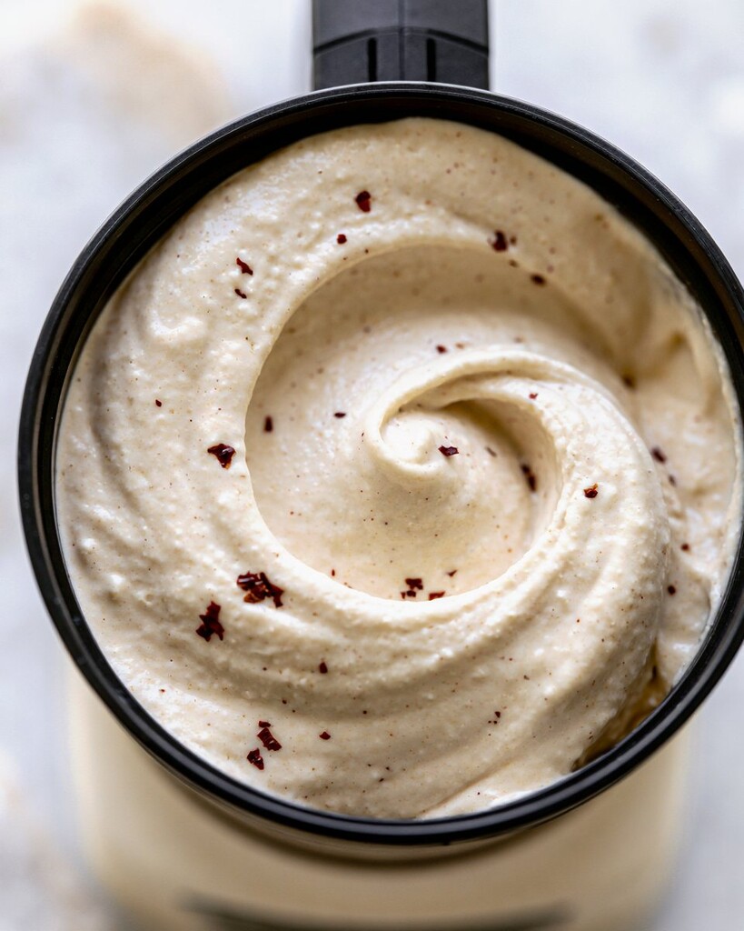 Smooth, creamy Alfredo sauce mixed inside a black blender pitcher