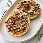 Toasted coconut apple samoas on a white plate with dark chocolate drizzle and flaky salt