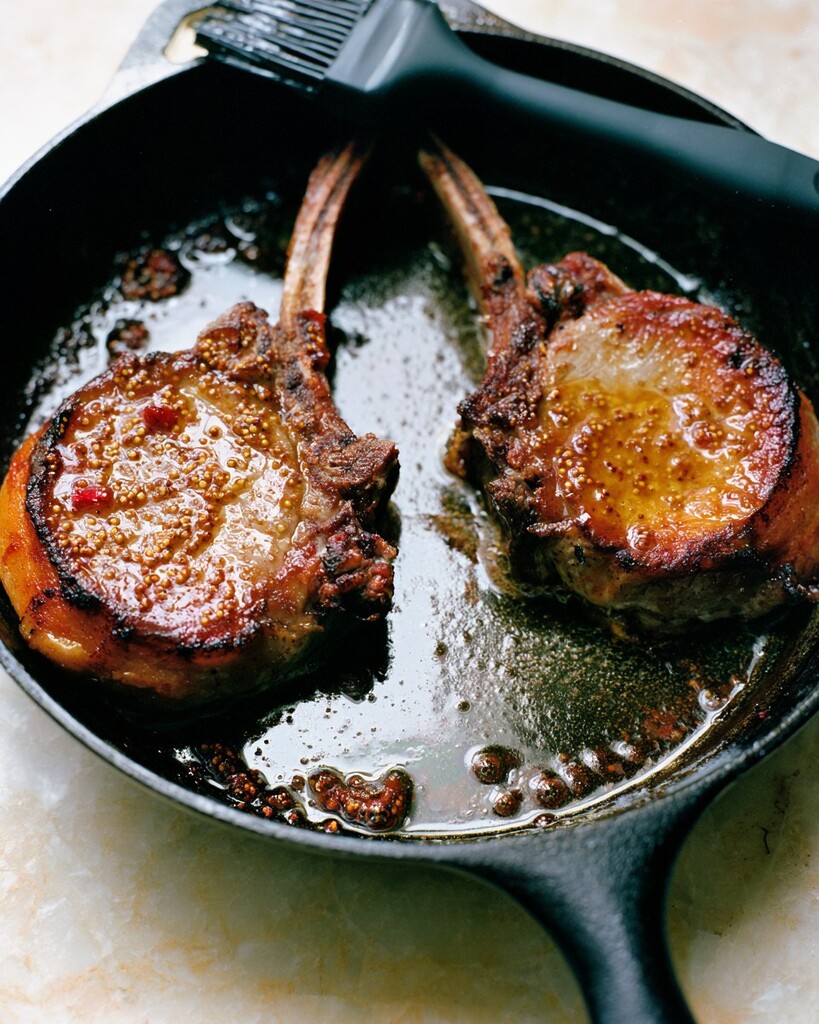 Hot honey pork chops with a shiny glazed crust sitting in a cast iron skillet