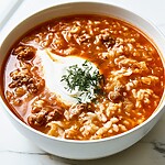 White bowl filled with cabbage roll soup showing tender ground beef, rice, and a swirl of sour cream with fresh dill