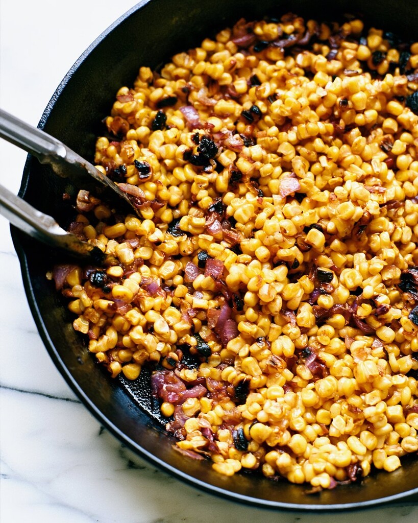 Corn kernels and chopped red onion charring in a hot cast iron skillet