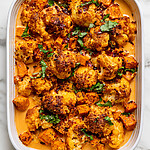 White ceramic baking dish filled with Marry Me vegetable bake showing a golden breadcrumb crust and fresh green basil on top