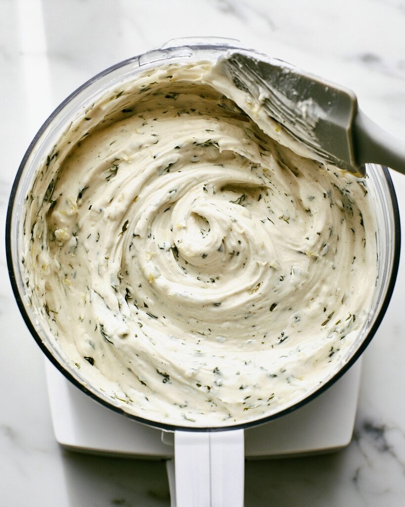 Whipped cottage cheese and green herbs blending inside a small food processor