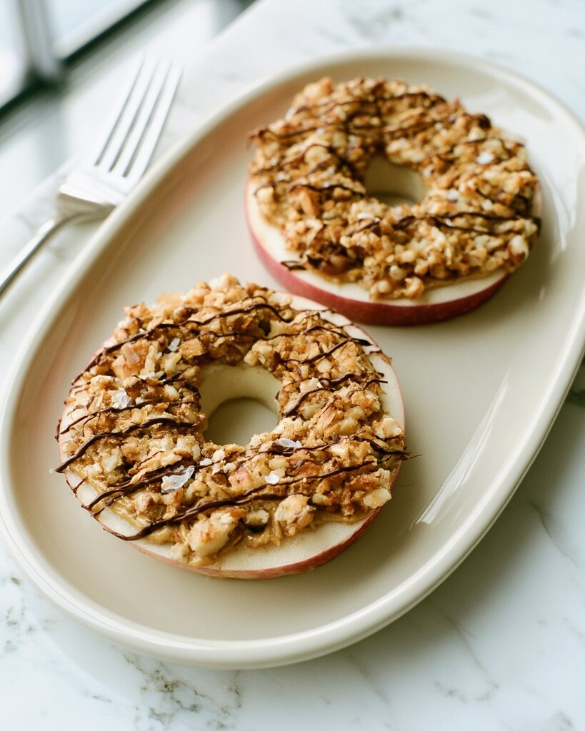 Toasted coconut apple samoas resting on a light plate showing a crisp layer and thin chocolate lines