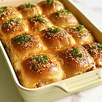 crack chicken sliders baking in a dish with a golden everything bagel butter topping