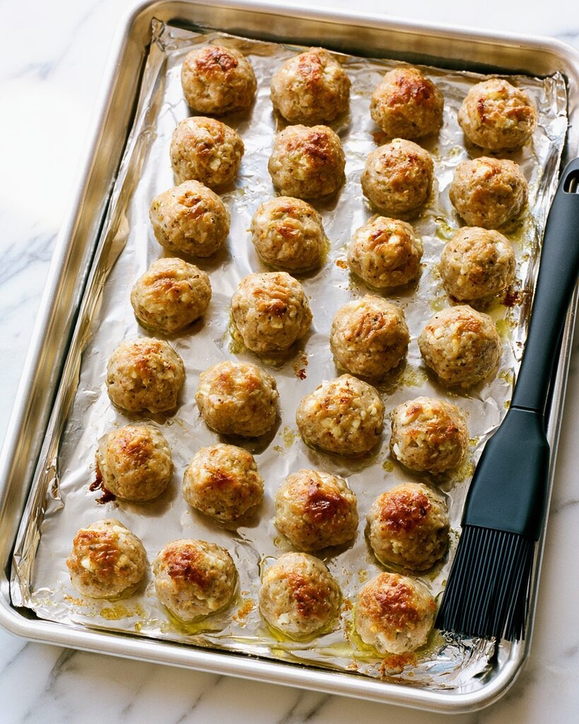 Golden brown baked turkey meatballs resting on a foil-lined sheet pan