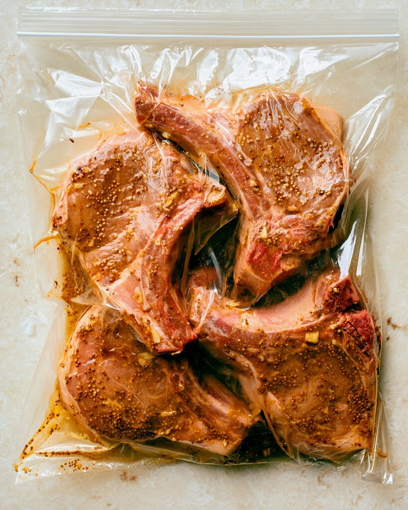 Raw pork covered in dark marinade inside a sealed plastic bag