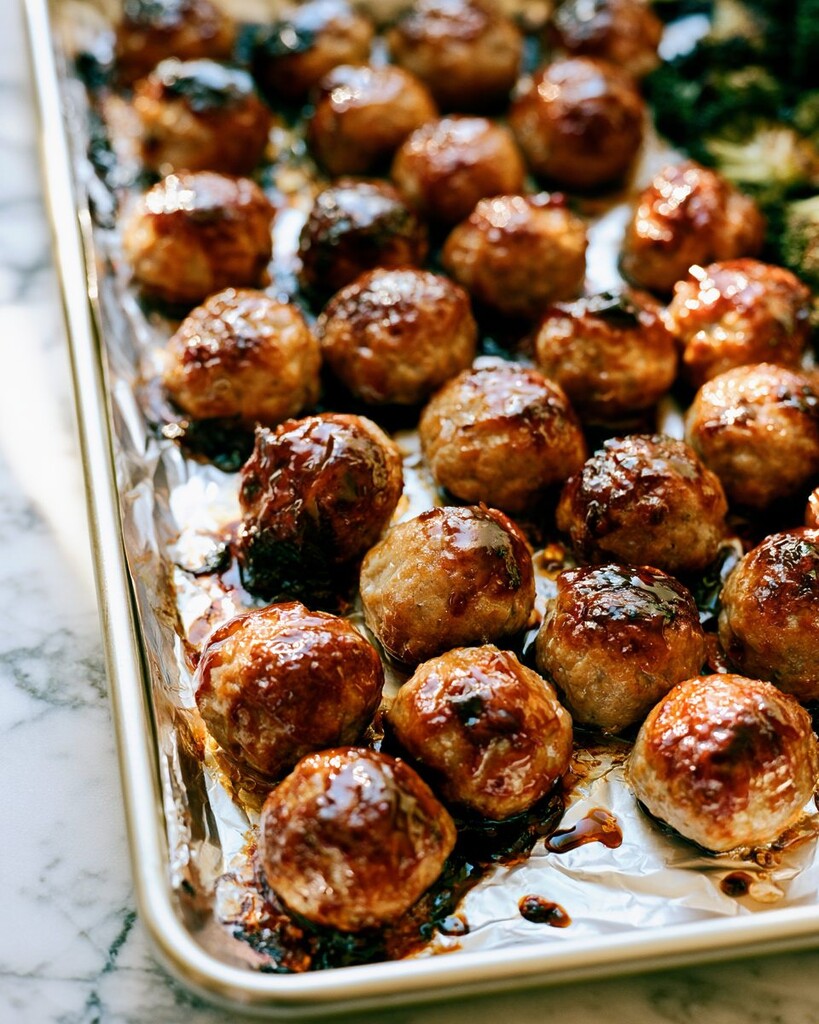 Baked teriyaki meatballs coated in a shiny caramelized glaze on a foil-lined pan