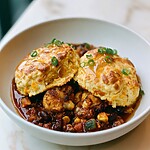 A bowl of cauliflower black bean chili served with two golden cheddar drop biscuits