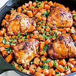 Cooked honey-chipotle chicken thighs coated in a glossy pan glaze over sweet potatoes with chopped cilantro