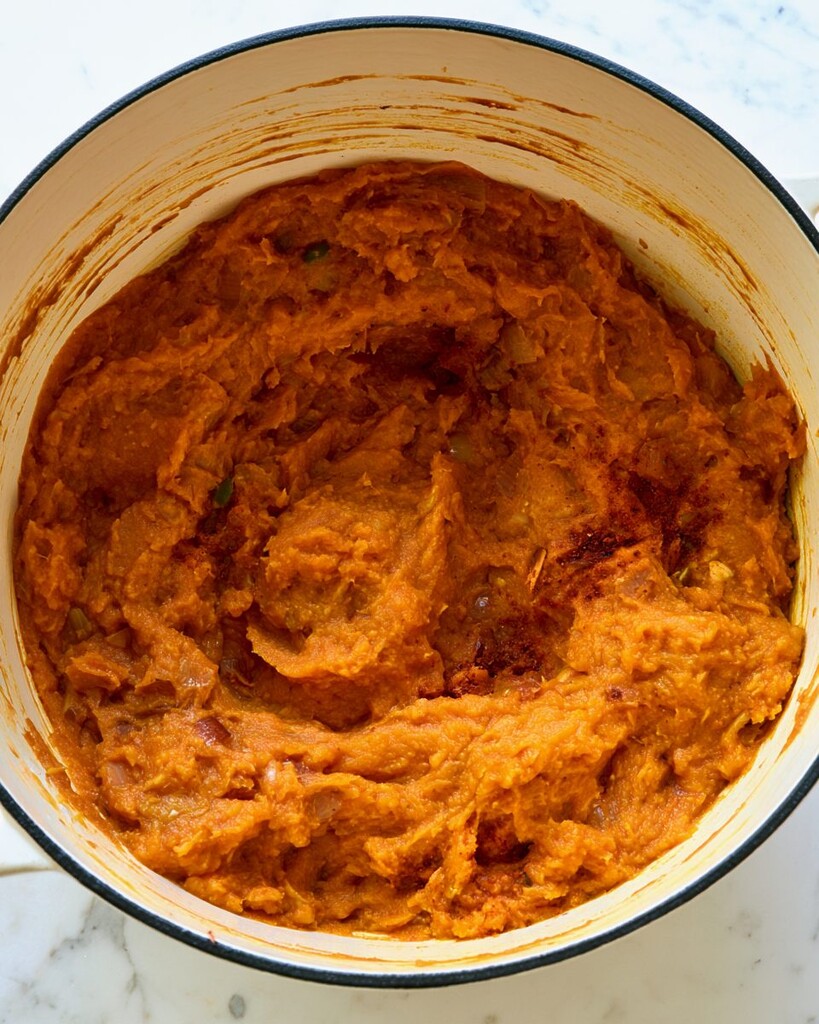 Thick spiced pumpkin puree cooking down in a heavy cast iron pot