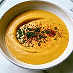 Thick velvety cheddar cheese sauce in a light bowl garnished with fresh chives and smoked paprika