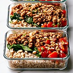 Glass containers of sticky ground turkey with brown rice, spinach, bell peppers, and cashews