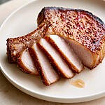 Thick slices of cooked pork showing a light juicy center and dark edges