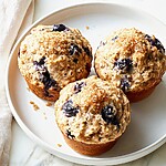 Three blueberry oatmeal muffins on a light plate showing golden crunchy sugar tops