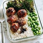 Glazed teriyaki meatballs served over white rice with roasted broccoli and edamame in a glass meal prep bowl