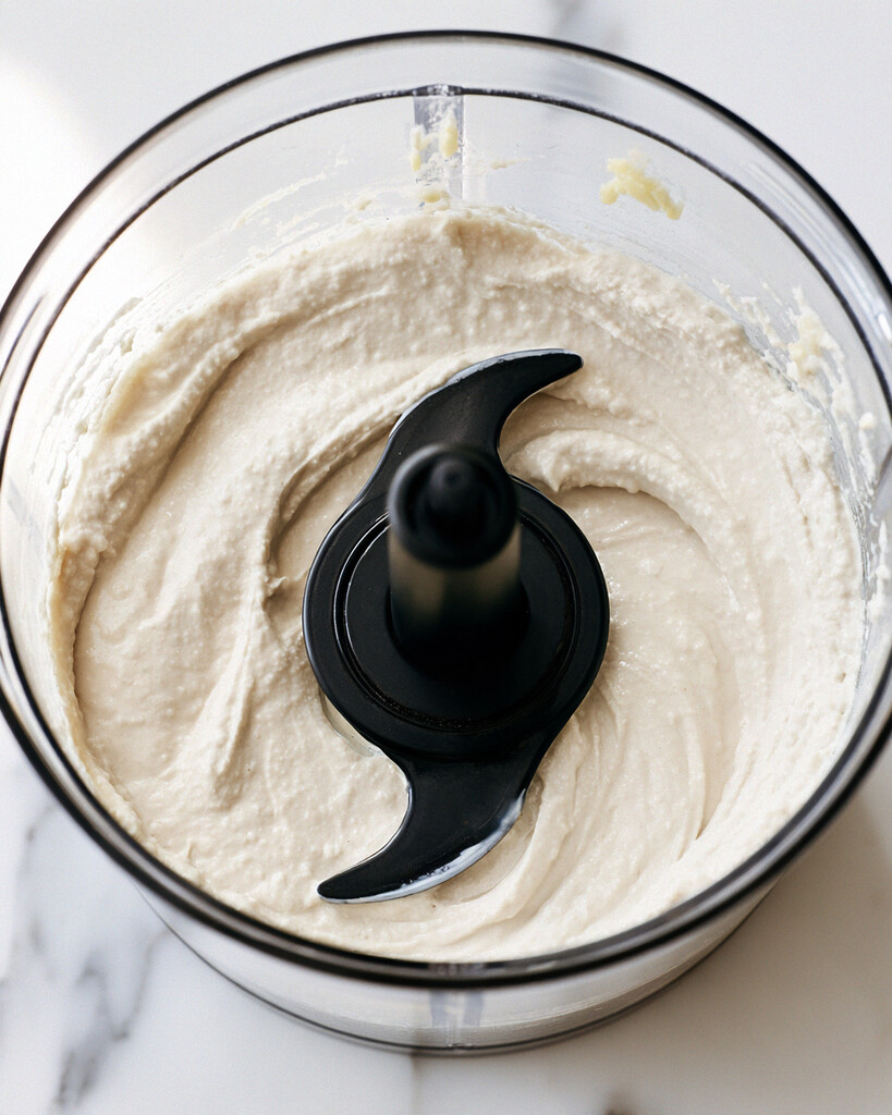 Pale and fluffy whipped tahini mixture in a food processor