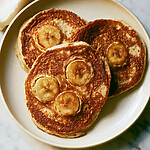 Single-Serve Caramelized Banana Cottage Cheese Pancakes Stack of three thick caramelized banana cottage cheese pancakes on a light ceramic plate