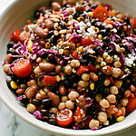 Ceramic bowl filled with cilantro-lime bean salad, loaded with red cabbage, corn, tomatoes, cheese, and pumpkin seeds