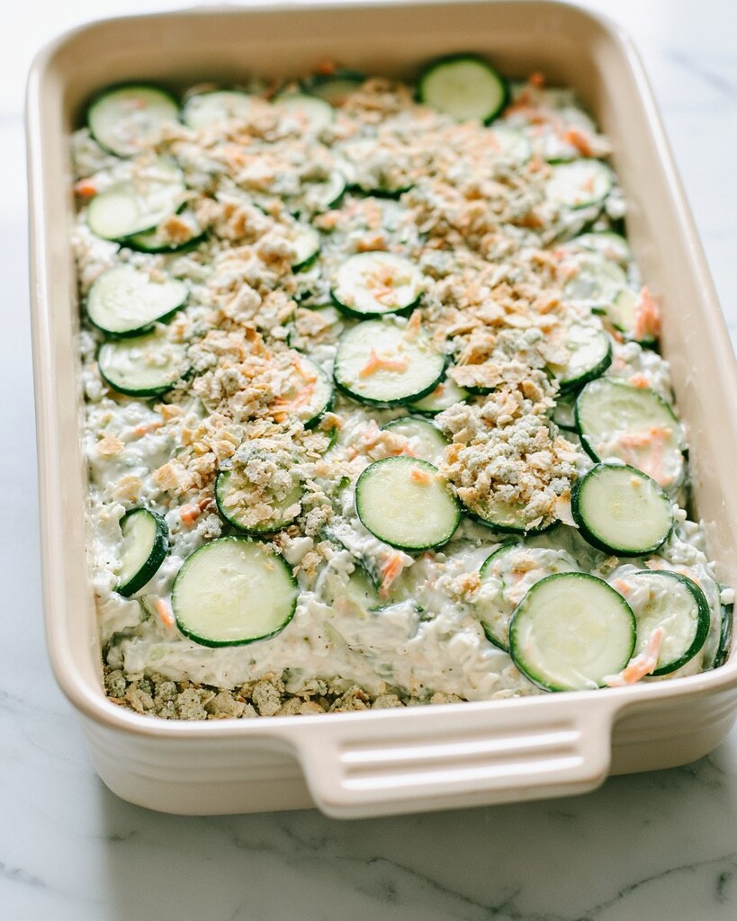 Spreading the creamy zucchini filling over a layer of stuffing crust in a rectangular baking dish