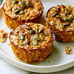 Firm pumpkin baked oatmeal cups served on a ceramic plate with browned edges and shiny pumpkin seeds