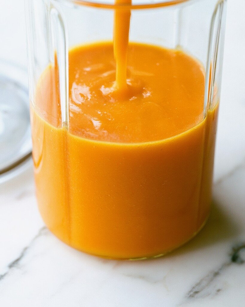 Smooth orange mango sauce poured into a clear glass bowl