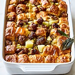 Close-up of baked croissant stuffing with golden crispy pieces and browned sausage topped with a hot honey drizzle