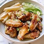 Glossy hot honey and cider-glazed wings plated next to fresh apple, celery, and scallions
