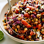 Spoon lifting a cohesive scoop of mixed beans, corn, and chopped vegetables