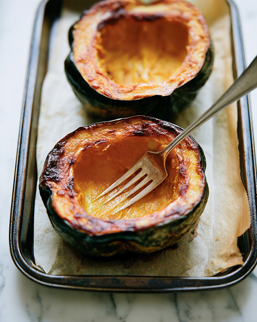 Halved and hollowed acorn squash roasted on a baking sheet with browned edges