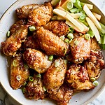 Hot Honey & Cider-Glazed Wings with Apple Celery Slaw Hot honey and cider-glazed wings arranged in a bowl with fresh apple and celery slaw