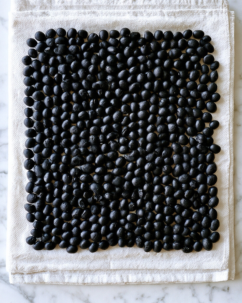 Rinsed black beans spread out on a towel to dry completely